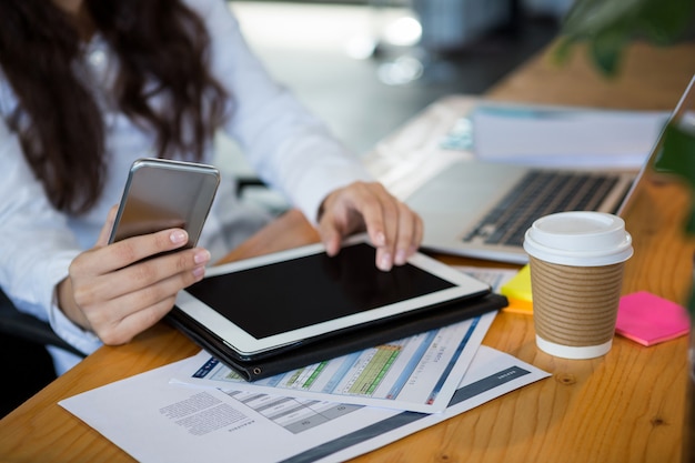 Ejecutivo de negocios con tableta digital y teléfono móvil en el escritorio