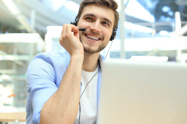 Ejecutivo de soporte al cliente masculino joven feliz que trabaja en la oficina.