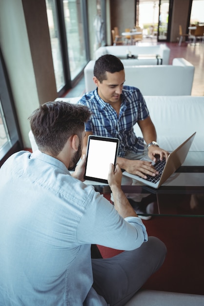 Ejecutivos con laptop y tableta digital en cafetería