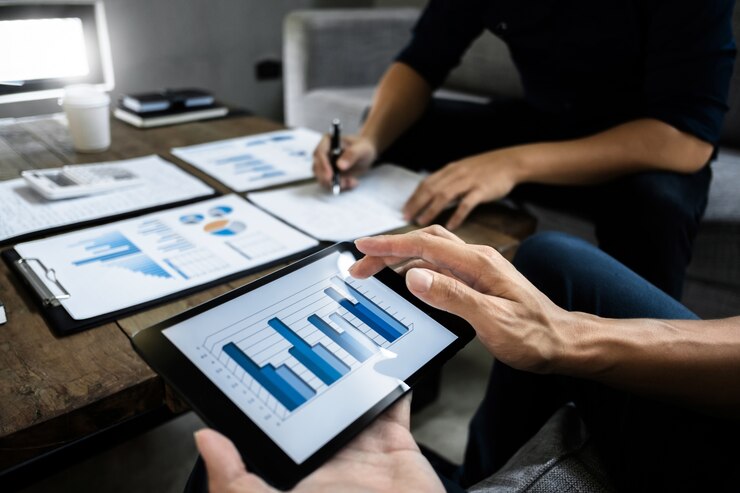Los ejecutivos de negocios inteligentes se asocian analizando la valoración en una tableta digital y papel de datos