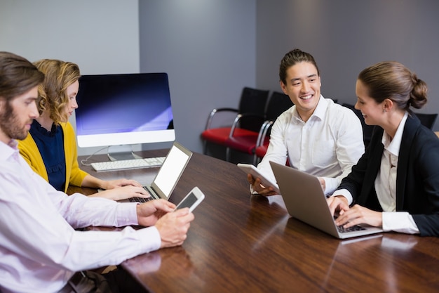 Ejecutivos de negocios que utilizan dispositivos electrónicos en la mesa de conferencias