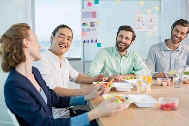 Ejecutivos de negocios sonrientes comiendo en la oficina