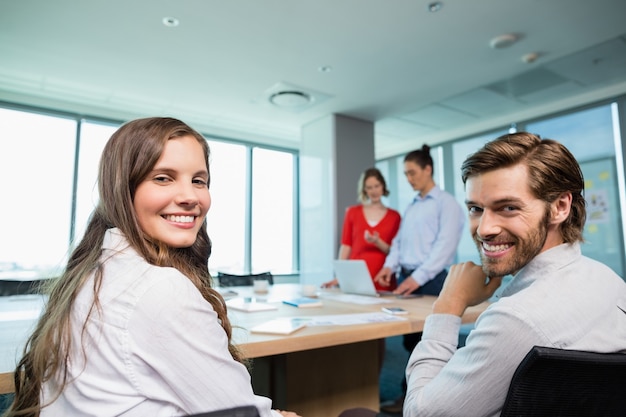 Ejecutivos de negocios sonrientes sentados juntos en la sala de conferencias