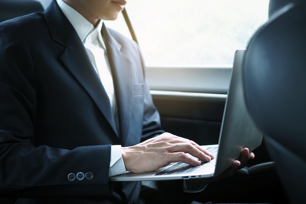 Los ejecutivos usan computadoras portátiles para trabajar mientras viajan y se sientan dentro del automóvil.