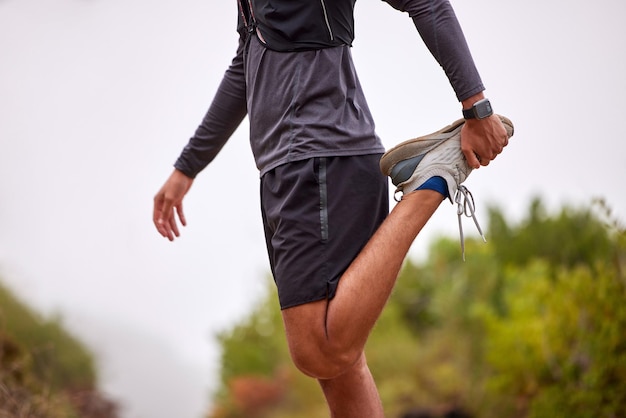 Foto ejercer el equilibrio y el hombre estirando las piernas en el sendero natural para correr entrenamiento de maratón y entrenamiento cardiovascular deporte cuerpo saludable y torso de atleta masculino calentar para energía de bienestar y fitness