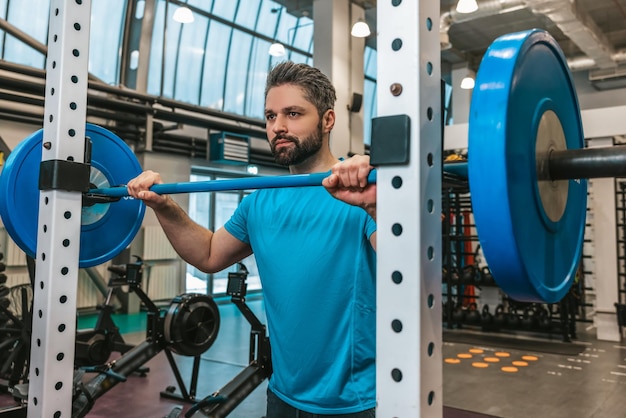 Ejercicio. Atleta guapo joven haciendo ejercicio con una campana de barra