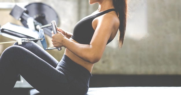 Ejercicio atractivo de la mujer del ajuste con la máquina del ejercicio de la barra en el gimnasio. Fitness Estilo de vida saludable y entrenamiento en el concepto de gimnasio.