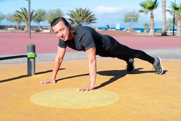 Ejercicio deportivo de hombres caucásicos que se flexionan en un campo deportivo al aire libre