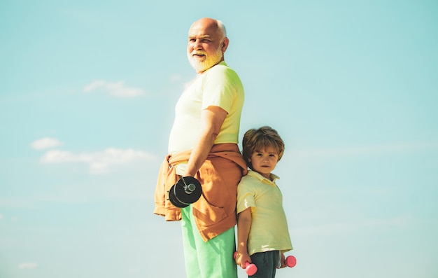 Ejercicio deportivo para niños, abuelo y nieto pequeño, practican ejercicios con pesas al aire libre levantando