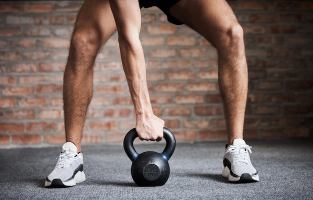 Ejercicio de entrenamiento con pesas rusas y manos de hombre para levantamiento de pesas, entrenamiento físico y desafío deportivo en el gimnasio