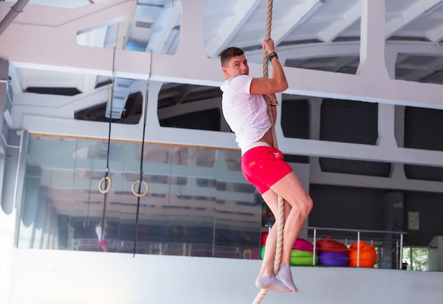 Ejercicio de escalada de cuerda de fitness en entrenamiento de gimnasio.