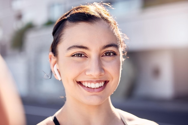 Ejercicio físico y selfie con una mujer escuchando música para hacer ejercicio y entrenamiento cardiovascular al aire libre en una ciudad Cara de retrato y sonrisa de mujer feliz por inspiración en las redes sociales