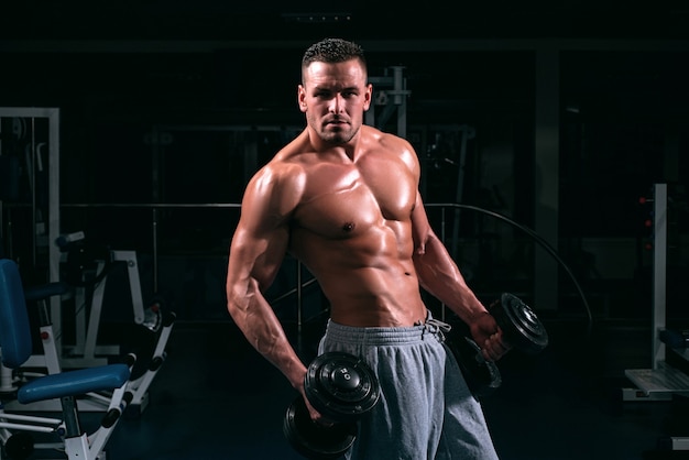 Ejercicio en el gimnasio. Entrenamiento deportivo. Hombre de fitness se centró en levantar una pesa.