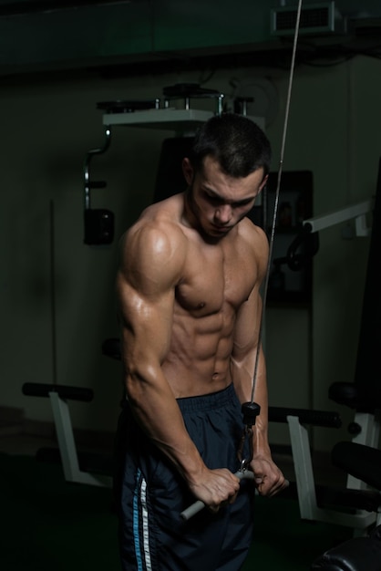 Ejercicio de hombre joven en el gimnasio que está realizando empujones de tríceps de dos brazos