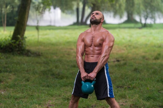 Ejercicio masculino de fitness joven con Kettle Bell Kettlebell Swing