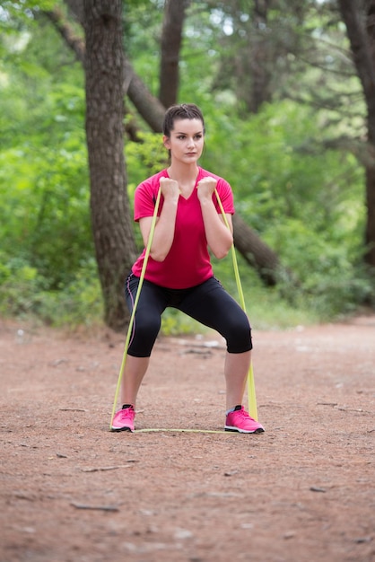 Ejercicio de mujer joven con banda de resistencia en el área boscosa del bosque Fitness Concepto de estilo de vida saludable