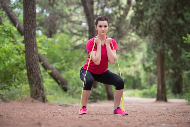 Ejercicio de mujer joven con banda de resistencia en el área boscosa del bosque Fitness Concepto de estilo de vida saludable