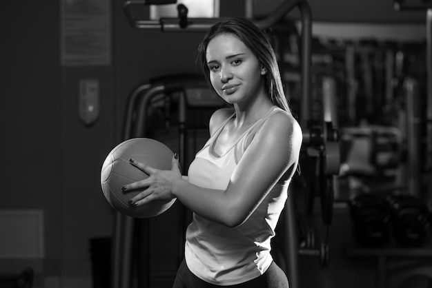 Ejercicio de mujer joven con pelota médica en el gimnasio