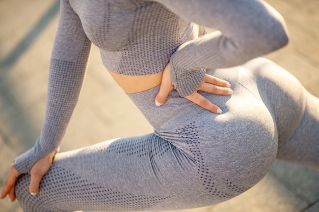 Ejercicio. Mujer joven en ropa deportiva gris con un entrenamiento fuera