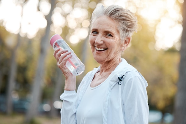 Ejercicio mujer mayor y botella de agua para entrenamiento físico en la naturaleza o retrato Mujer anciana madura e hidratación para el bienestar, la salud y el entrenamiento al aire libre para la jubilación cardiovascular o relajarse