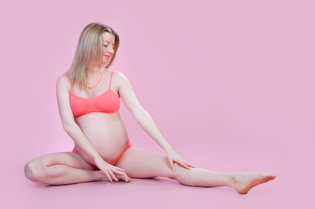 Ejercicio de yoga de mujer embarazada. Embarazo Cuidado de la salud prenatal y Gimnasia deportiva. La madre está en el estudo sobre el fondo rosa.