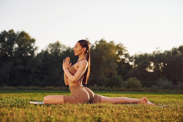 Ejercicios de columna Mujer joven en ropa de yoga está al aire libre en el campo