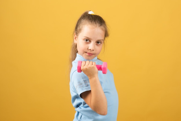 Ejercicios de ejercicios para niños con mancuernas de fitness. Niña deportiva con mancuernas. Niños de retrato deportivo.