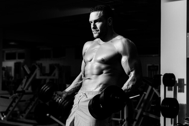 Ejercicios de mancuernas de bíceps culturista en entrenamiento de gimnasio y deportista de entrenamiento con t desnudo sin camisa
