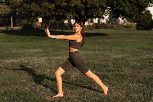 Foto ejercicios de meditación qigong al aire libre una chica asiática en forma hace entrenamiento chino en la hierba verde del parque