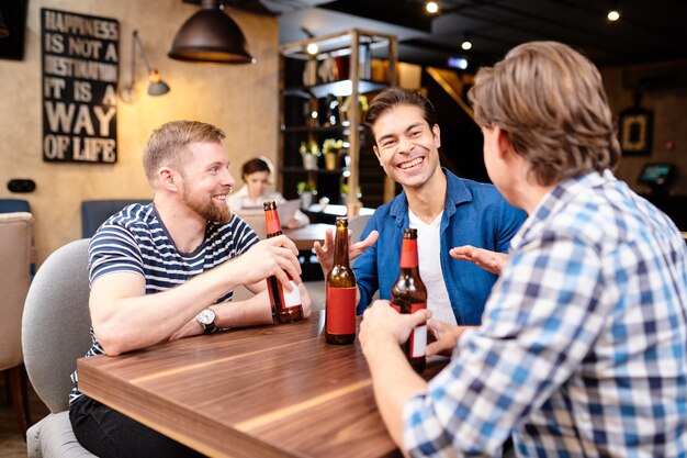 Ekstatische Freunde lachen, während sie Bier in der Bar trinken