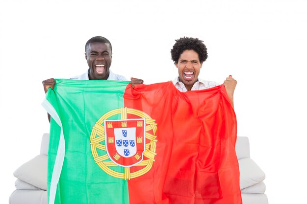 Ekstatische Portugal-Fans, die auf der Couch mit Flagge sitzen