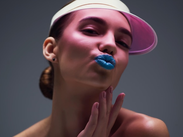 Ela adora se destacar Foto de estúdio de uma jovem atraente usando um boné retrô rosa posando contra um fundo cinza