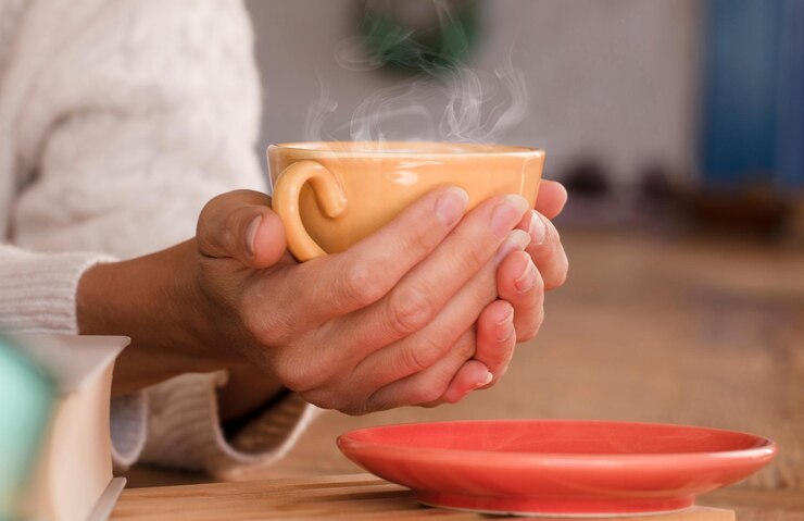 Foto ela aquece as mãos com uma xícara de café quente. concentre-se na xícara