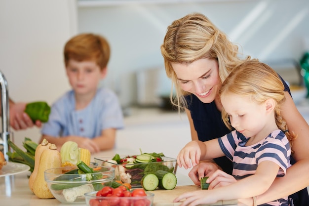 Ela é uma ótima chef de cozinha foto recortada de uma mãe cozinhando junto com seus dois filhos em casa