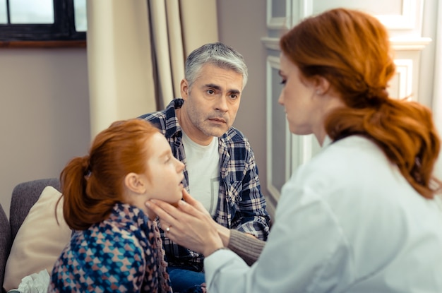 Ela esta bem. Pai triste e preocupado olhando para o médico enquanto quer saber o estado de saúde de sua filha