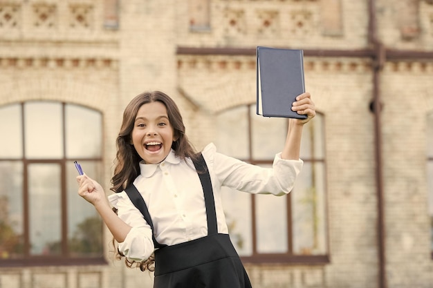 Ela fez isso Aluno feliz celebrando o exame de aprovação Criança pequena com gesto de vencedor segura papel de exame Exame ou teste de conhecimento Período de exame Escola e educação