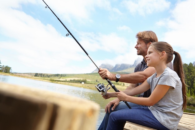 Ela já é uma pescadora experiente Foto de um pai mostrando à filha como pescar