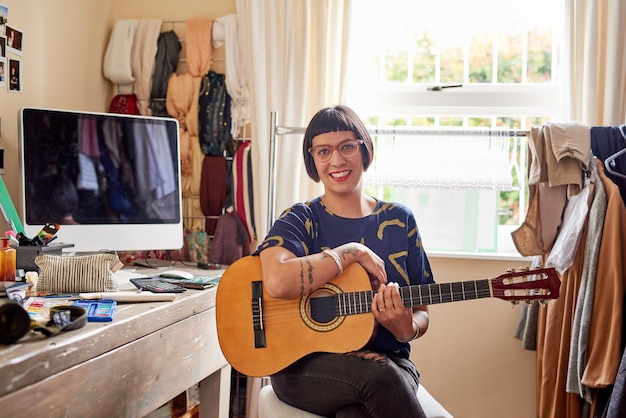 Ela tem música em sua alma Retrato de uma jovem elegante sentada em seu quarto eclético tocando violão