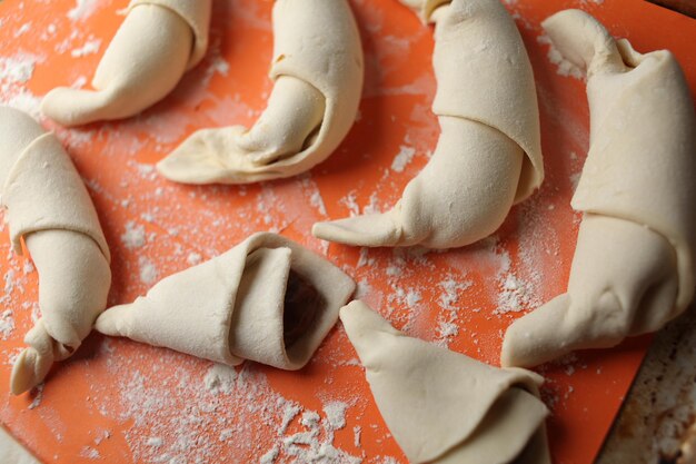 Elaboración de croissants clásicos. Rollos de media luna antes de hornear. croissants en una bandeja. Productos de pastelería francesa, panadería. Masa para croissants. Elaboración de croissants.