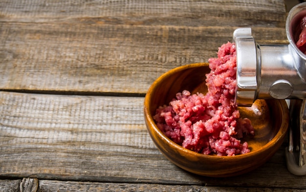 Elaborado a base de carne. Cocinar la picadora de carne picada. Sobre una mesa de madera. Espacio libre para texto.