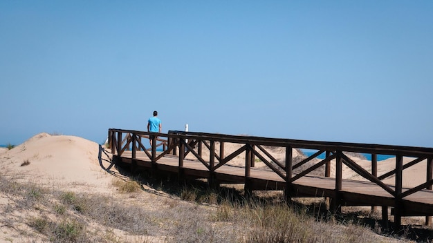 Elche espanha homem de abril caminhando sozinho por uma ponte de madeira nas dunas perto do mar