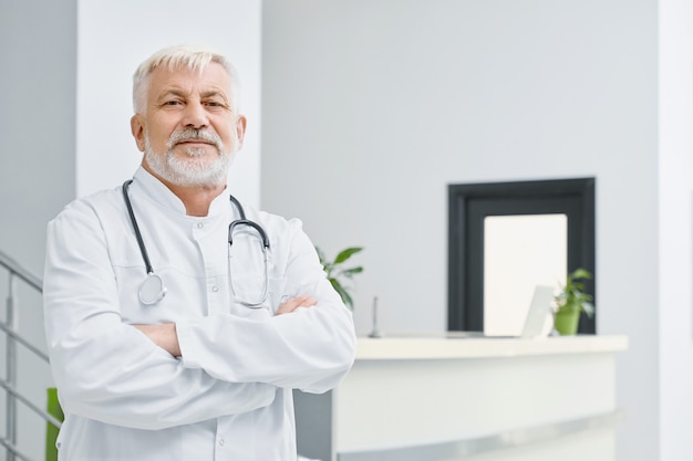 Eldery doctor en abrigo con los brazos cruzados.