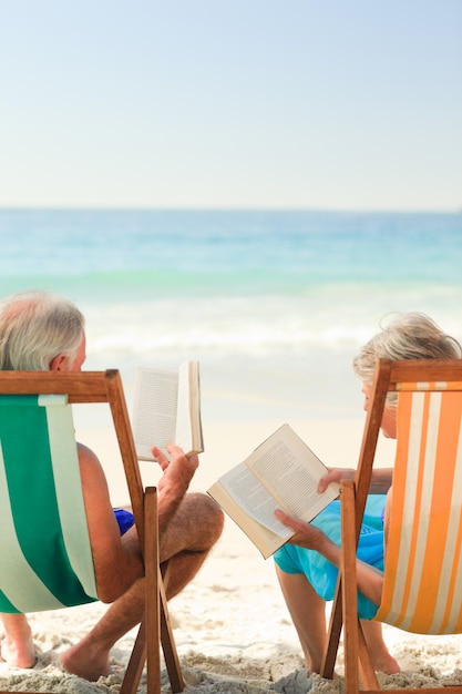 Eldery pareja leyendo en la playa