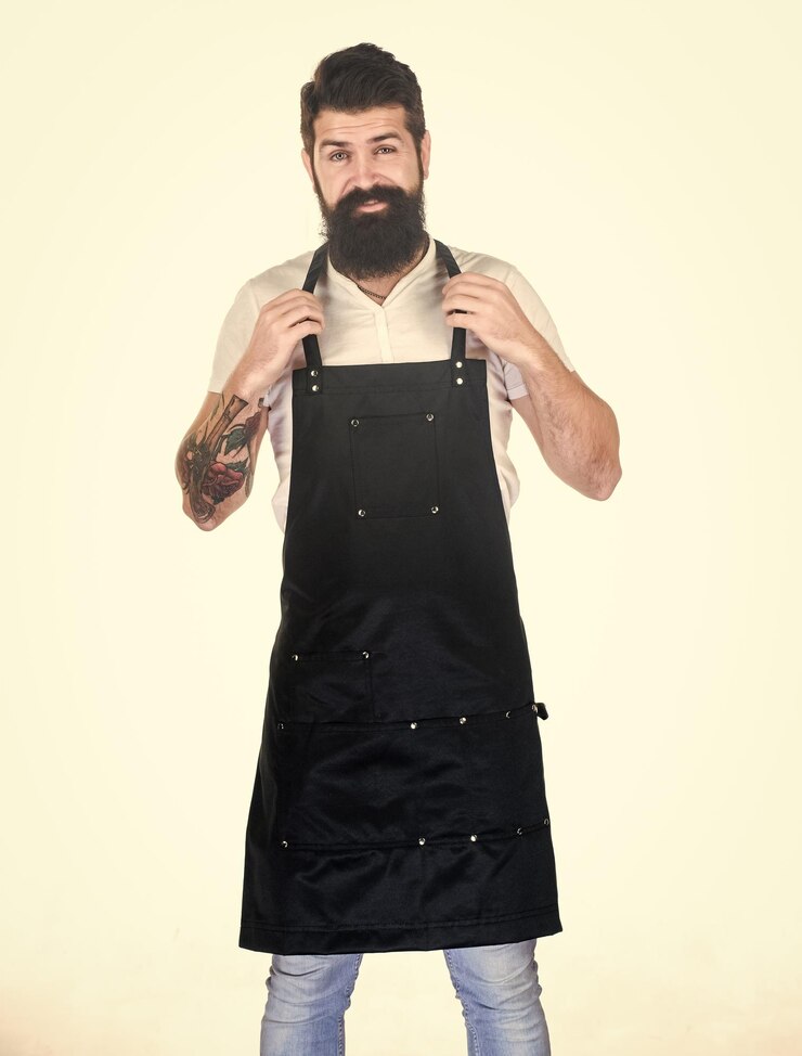 Foto ele é o melhor barbeiro barbudo usando avental de barbeiro hipster em avental de trabalho com vários bolsos estilista de cabelo em barbearia barbearia ou salão de cabeleireiro