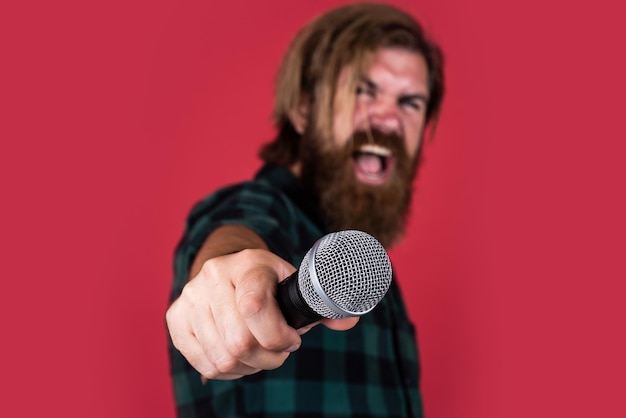 Ele é um cantor estiloso brutal de estrela do rock cantando no karaokê hipster maduro com barba canta música cara caucasiano brutal com microfone homem barbudo conceito de foco seletivo de música