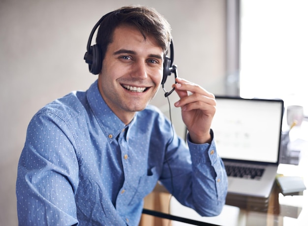 Ele está assumindo vários papéis de negócios no momento Retrato de um jovem empresário usando um fone de ouvido enquanto está sentado em sua mesa