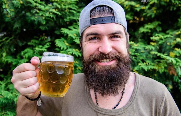 Ele está de humor feliz Bebedor feliz Hipster feliz segurando a caneca de cerveja Homem barbudo feliz sorrindo com cerveja na natureza Refrescando seu espírito