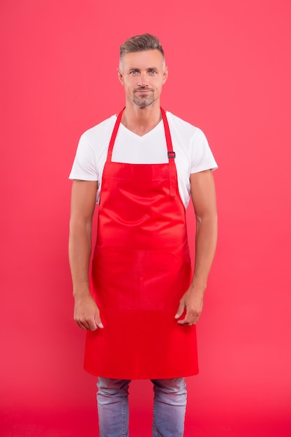 Ele está esperando. barista experiente e maduro usa avental vermelho. jovem empresário de cafeteria. Uniforme de barista masculino. homem com barba por fazer trabalhar como barista. Trabalho em meio período. Retrato de homem confiante barista.