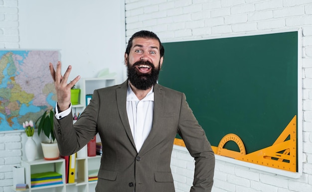 Ele está falando de um estudante do sexo masculino de educação informal na sala de aula da escola enquanto a aula está pronta para passar no exame aprendendo o assunto homem feliz com barba vestindo terno formal processo de estudo