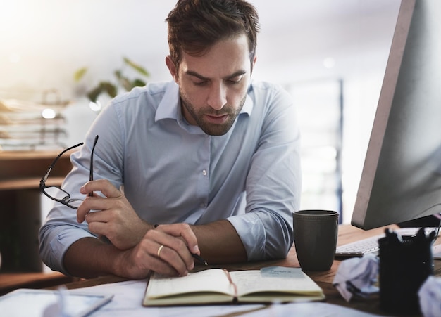 Ele fica de olho em cada detalhe Foto de um jovem empresário trabalhando até tarde em um escritório